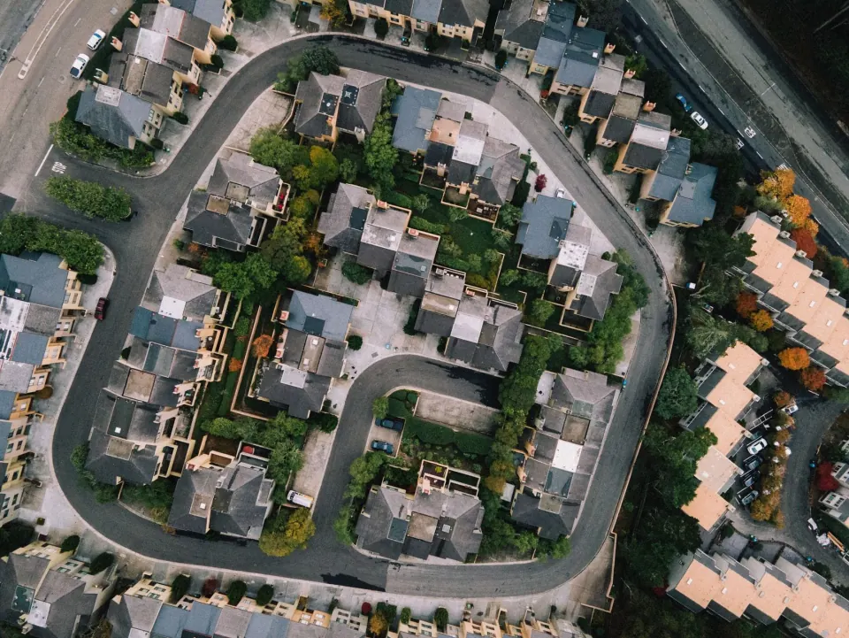 Overhead view of a suburban development with townhome rows curving around a looping street