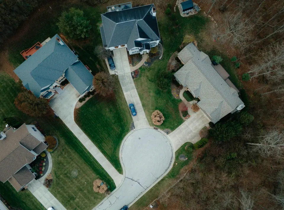 Aerial view of single family homes around a cul-de-sac with wide lawns and wooded lots