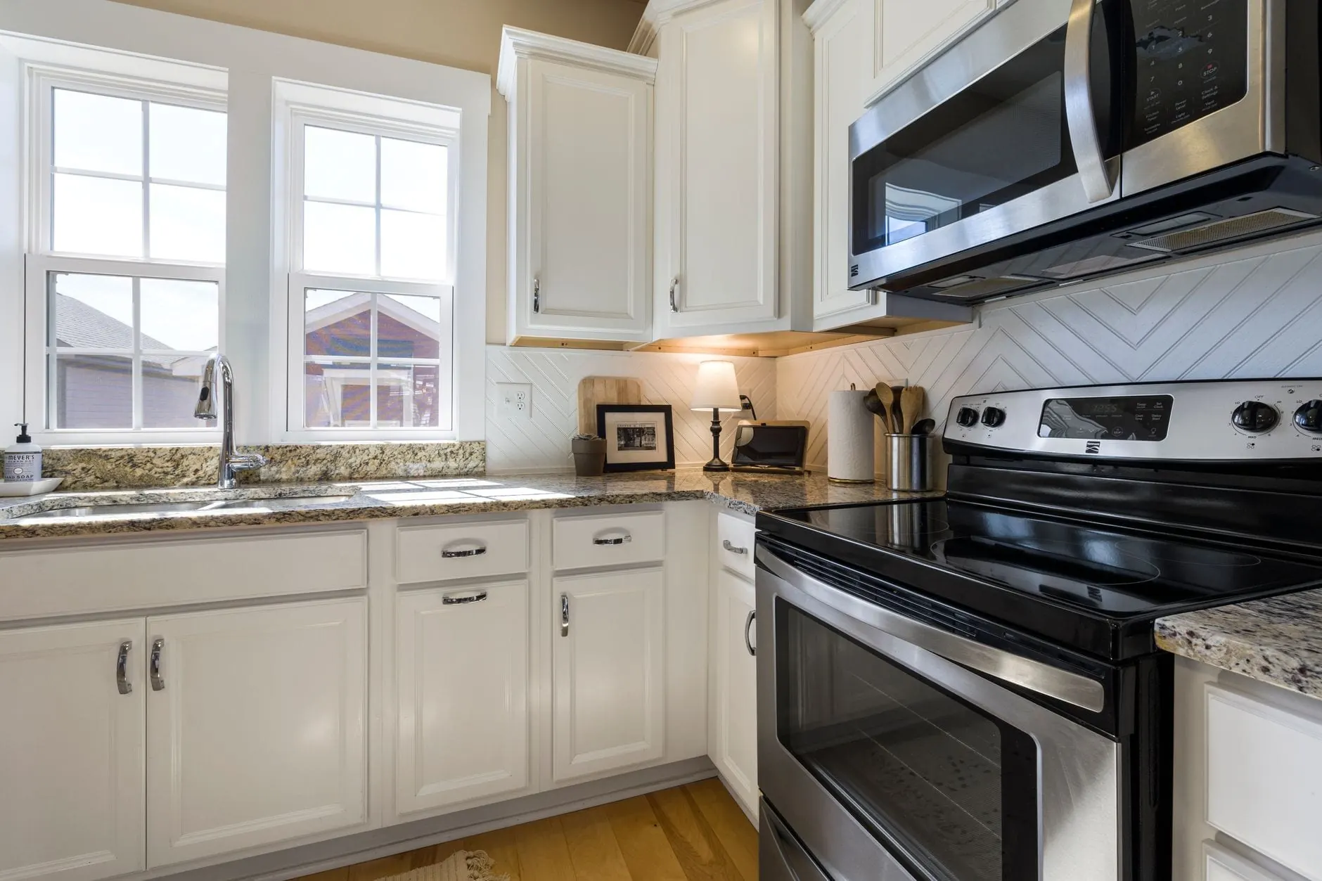 Kitchen counters in a speckled stone-look finish wrapping around white cabinets and a stainless range